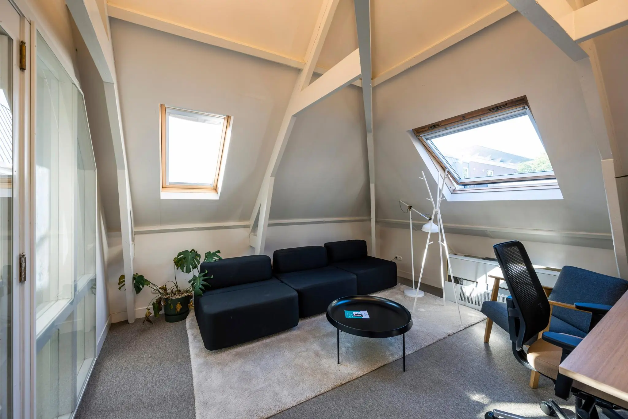 Zolderkamer aan de Prof. Tulpstraat met zwarte bank, dakramen en modern interieur.